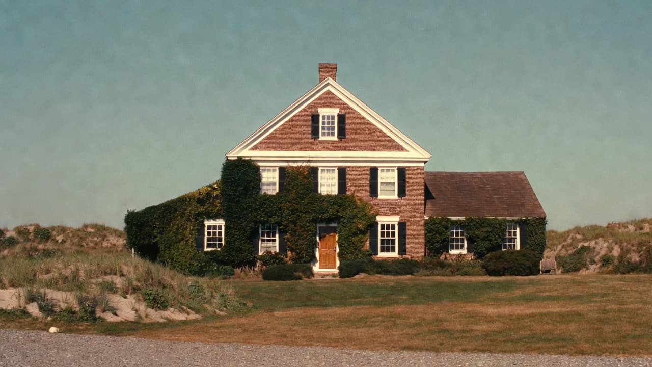 A brick colonial building at the edge of dune grass, late light.