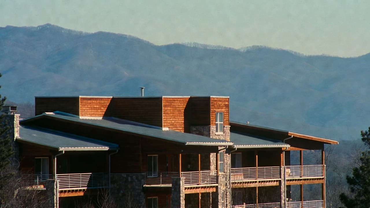 A timber lodge on a ridgeline above the Smoky Mountains at dusk.