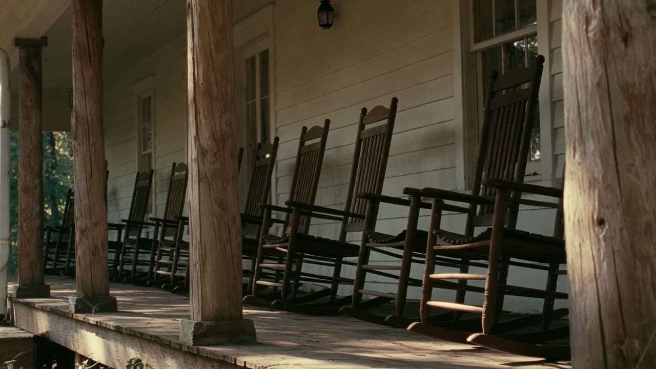 Empty rocking chairs lined along a covered porch.